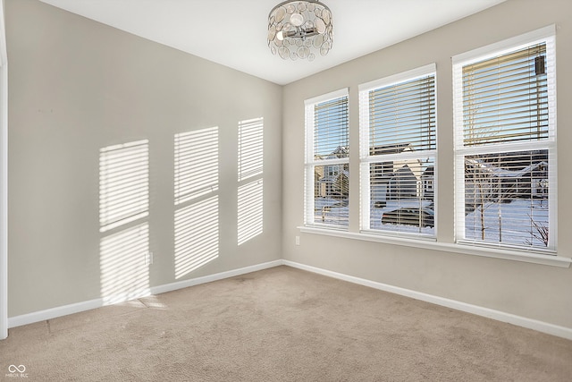 unfurnished room featuring carpet and a chandelier