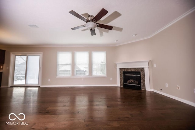 unfurnished living room featuring a tiled fireplace, crown molding, dark hardwood / wood-style flooring, and ceiling fan