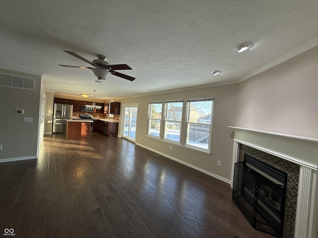 unfurnished living room with a tiled fireplace, ornamental molding, and dark wood-type flooring