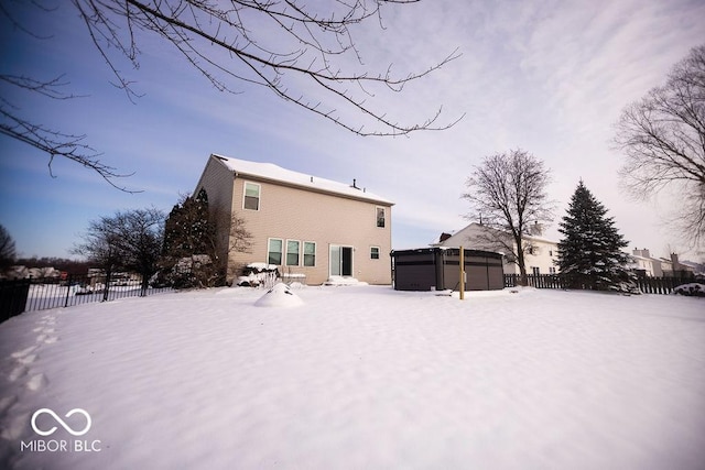 snow covered rear of property with a jacuzzi