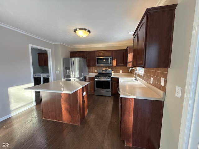 kitchen with sink, separate washer and dryer, a kitchen island, stainless steel appliances, and backsplash