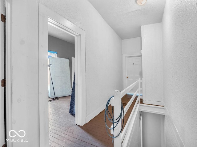 corridor featuring hardwood / wood-style floors and a textured ceiling