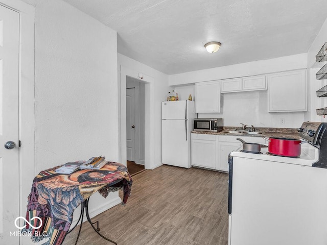 kitchen featuring range with electric stovetop, light hardwood / wood-style floors, white cabinets, and white fridge