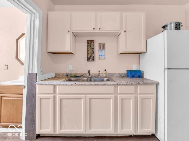 kitchen with white fridge, sink, and white cabinets