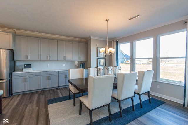 dining room with a notable chandelier, crown molding, and dark wood-type flooring