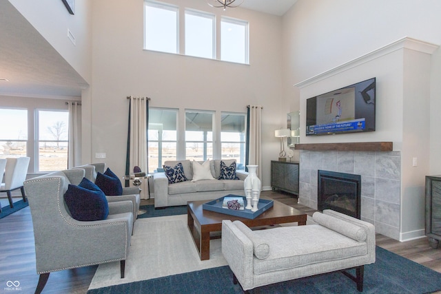 living room with a tile fireplace, hardwood / wood-style floors, and a towering ceiling