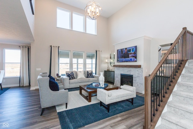 living room featuring a tile fireplace, hardwood / wood-style floors, a towering ceiling, and a chandelier