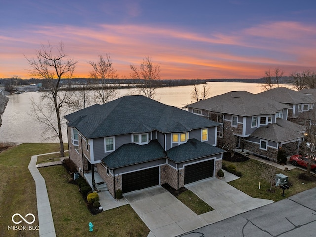 view of front of house featuring a lawn, a garage, and a water view