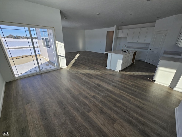 kitchen featuring white cabinetry, sink, dark hardwood / wood-style flooring, a kitchen island with sink, and a water view