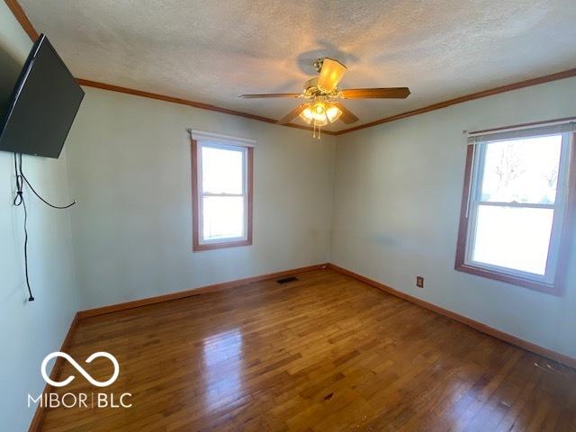 spare room with wood-type flooring, plenty of natural light, and ornamental molding