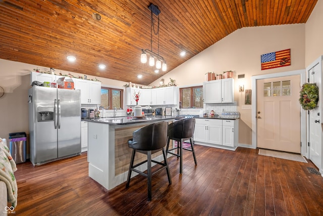 kitchen featuring stainless steel fridge, tasteful backsplash, pendant lighting, a center island, and white cabinetry