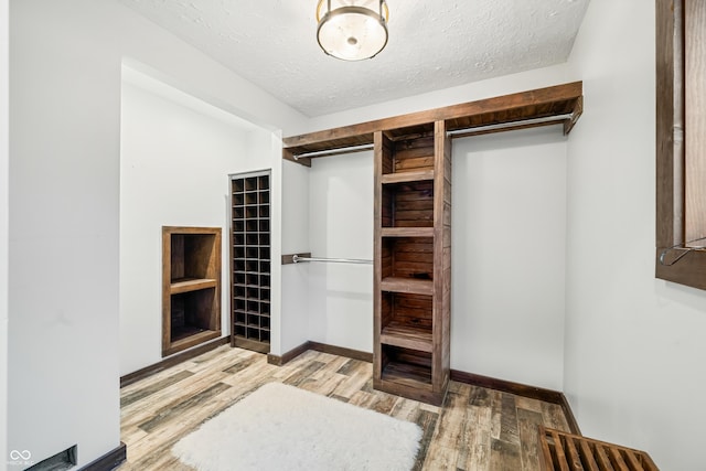 walk in closet with light hardwood / wood-style floors