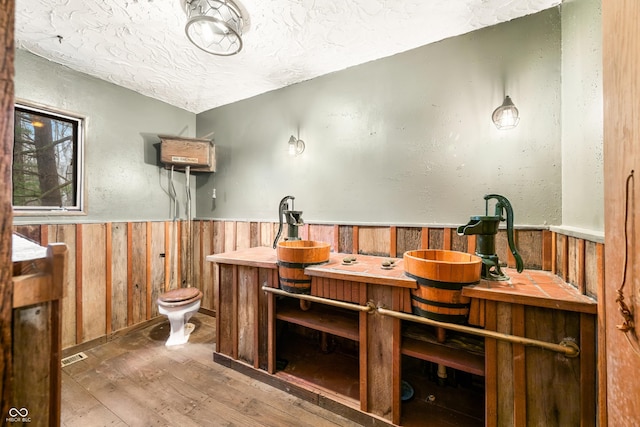 bathroom featuring hardwood / wood-style flooring, toilet, and a textured ceiling