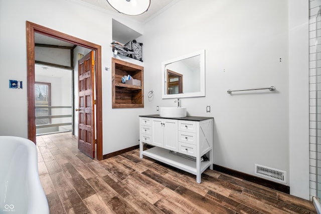 bathroom with hardwood / wood-style flooring, vanity, crown molding, and a bath