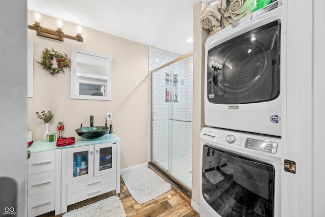 clothes washing area featuring sink, wood-type flooring, and stacked washer and dryer