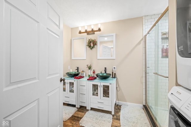 bathroom featuring stacked washer / dryer, vanity, an enclosed shower, and a notable chandelier