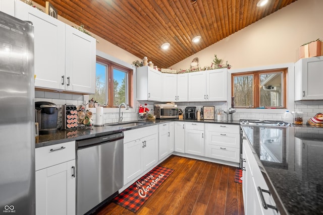 kitchen featuring sink, vaulted ceiling, decorative backsplash, white cabinets, and appliances with stainless steel finishes