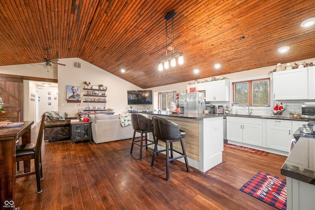 kitchen featuring decorative backsplash, appliances with stainless steel finishes, a kitchen island, pendant lighting, and white cabinetry