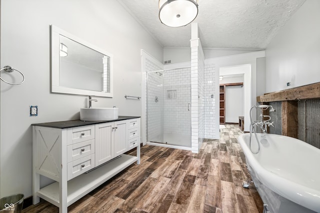 bathroom with vanity, a textured ceiling, vaulted ceiling, and separate shower and tub