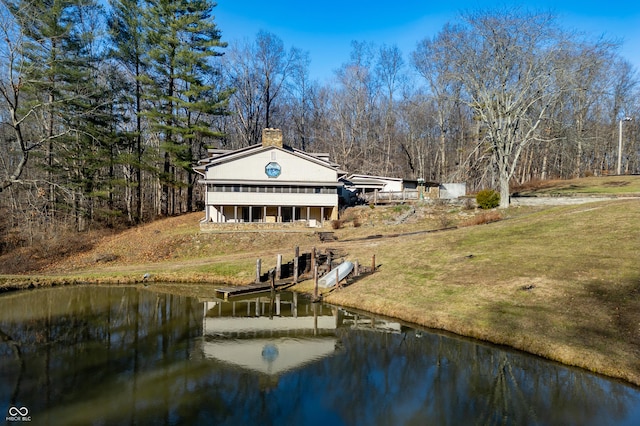 back of house featuring a water view and a lawn