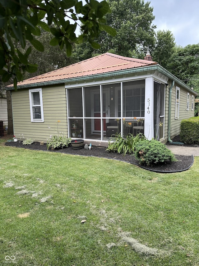 rear view of house featuring a sunroom and a yard