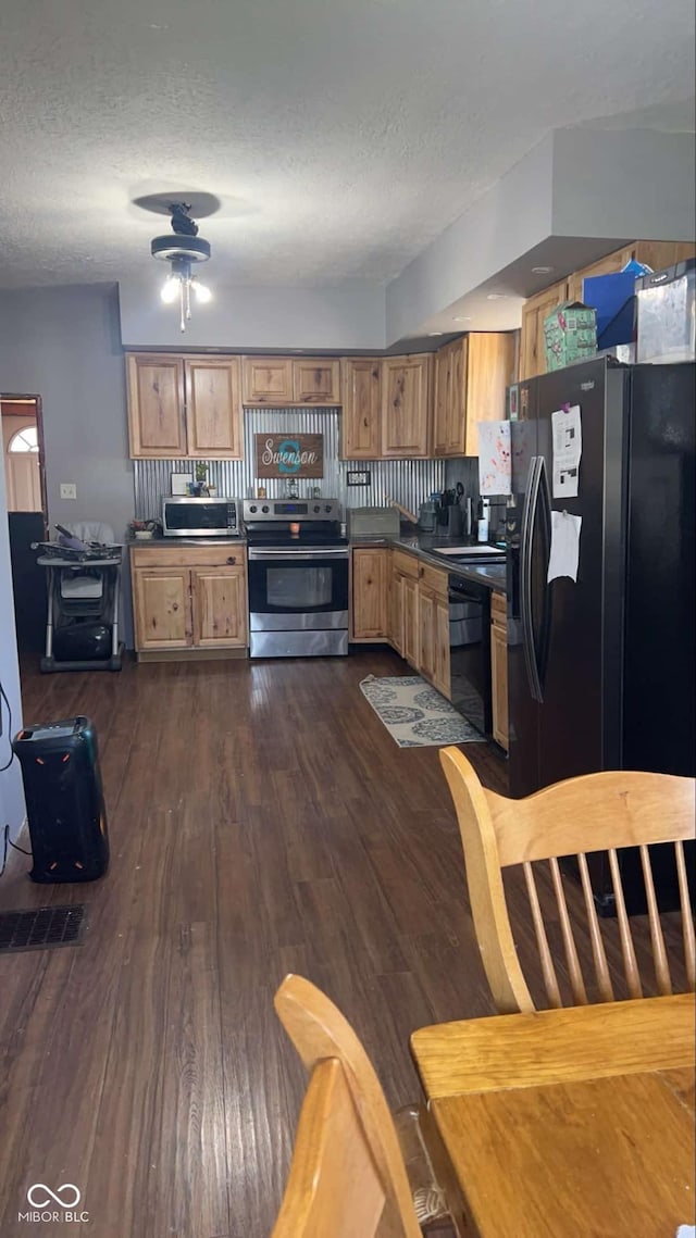 kitchen featuring dark wood-type flooring, black appliances, a textured ceiling, and sink