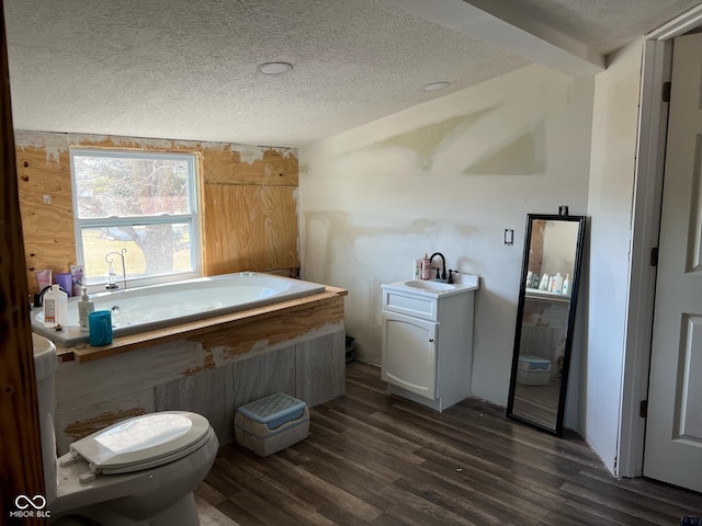 bathroom featuring beam ceiling, hardwood / wood-style floors, a textured ceiling, toilet, and vanity