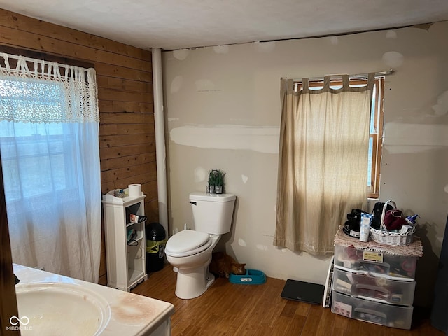 bathroom with wood-type flooring, vanity, toilet, and wooden walls