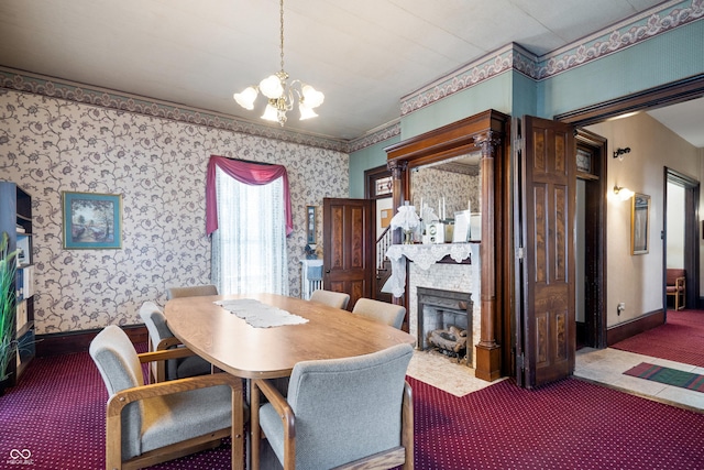 dining room featuring crown molding, carpet floors, a fireplace, and a chandelier