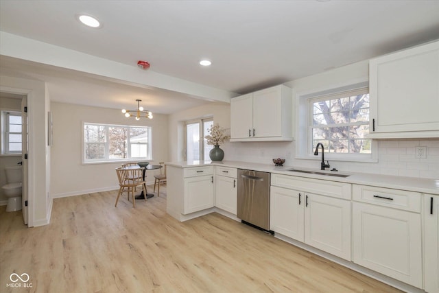 kitchen with sink, dishwasher, white cabinets, decorative light fixtures, and kitchen peninsula