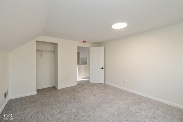 unfurnished bedroom with light carpet, vaulted ceiling, and a closet