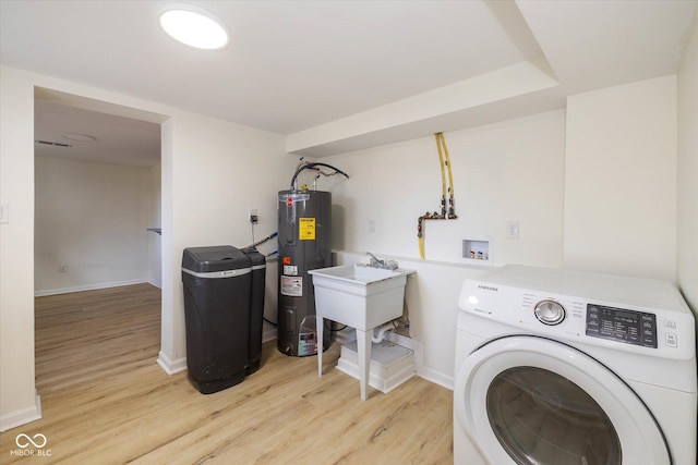 washroom with washer / dryer, electric water heater, sink, and light wood-type flooring