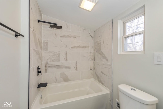 bathroom with tiled shower / bath, vaulted ceiling, and toilet