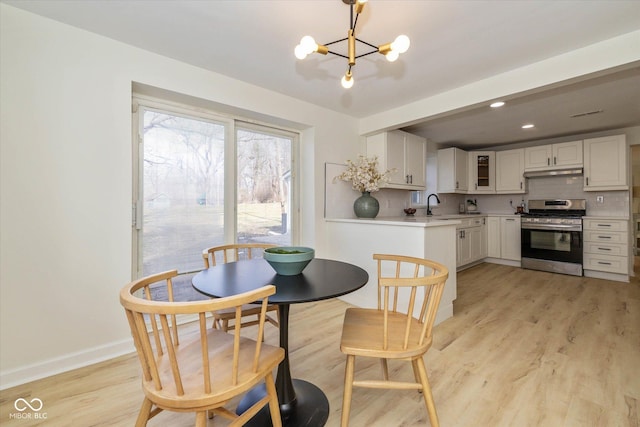 dining area featuring sink, an inviting chandelier, and light wood-type flooring