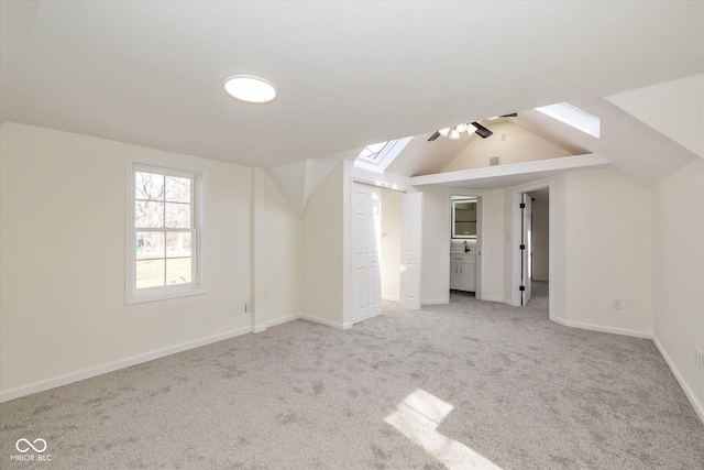 additional living space featuring light colored carpet and vaulted ceiling with skylight