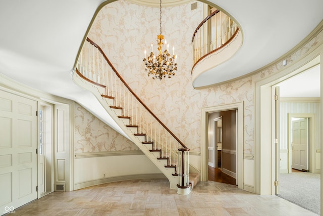 stairway with a chandelier, parquet floors, and ornamental molding