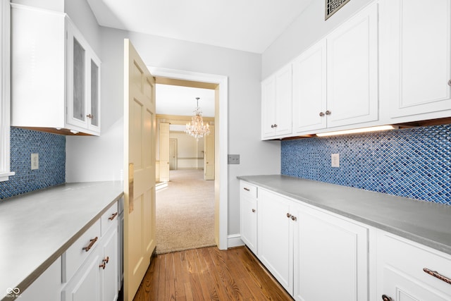 kitchen with white cabinetry, hanging light fixtures, dark hardwood / wood-style floors, and an inviting chandelier