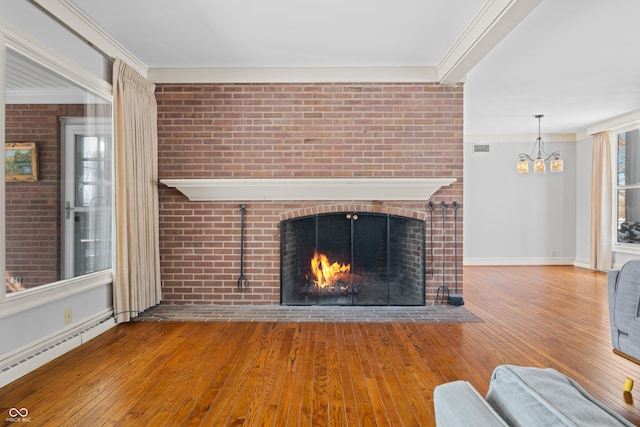 unfurnished living room featuring a brick fireplace, an inviting chandelier, brick wall, a baseboard heating unit, and ornamental molding