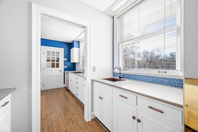 kitchen featuring white cabinets, light wood-type flooring, dishwasher, and sink