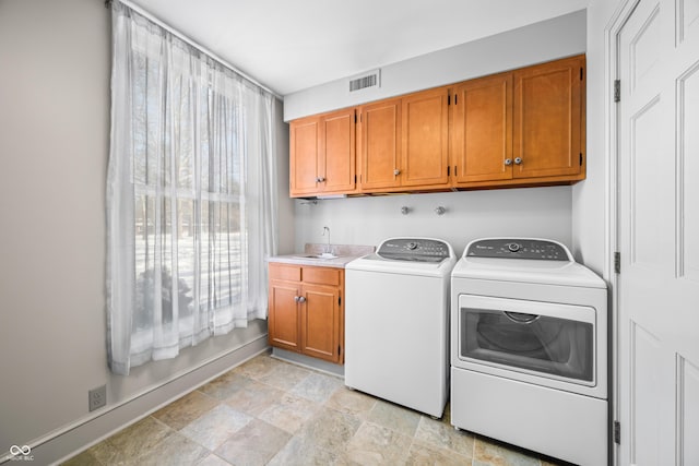 laundry room with cabinets, washing machine and dryer, and sink