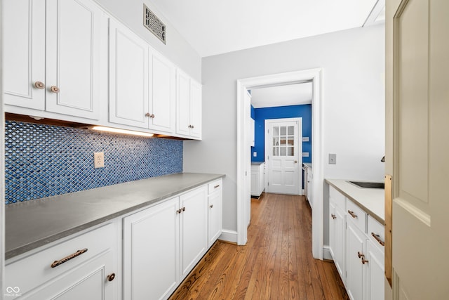 kitchen featuring decorative backsplash, white cabinetry, and light hardwood / wood-style flooring