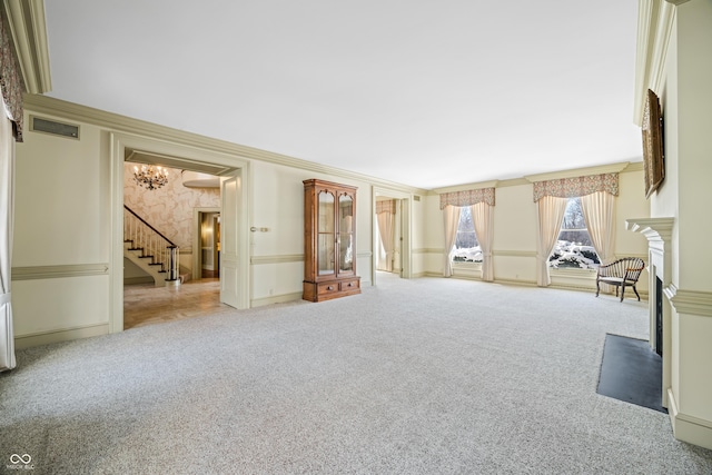 unfurnished room with carpet floors, ornamental molding, and an inviting chandelier