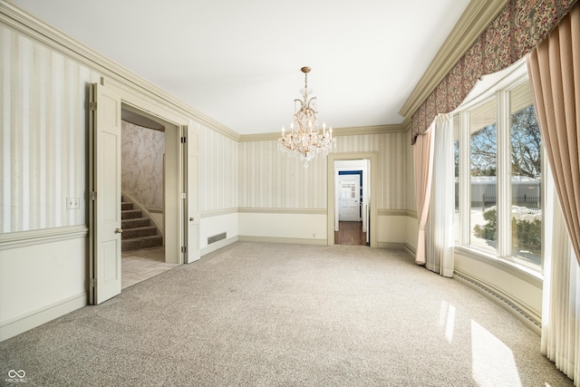 carpeted empty room with a chandelier and ornamental molding