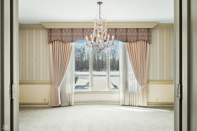 spare room featuring crown molding, carpet floors, and a notable chandelier