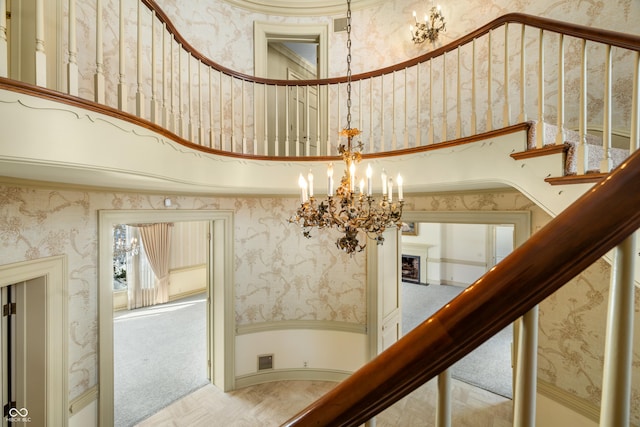 staircase with a chandelier, a towering ceiling, and carpet floors