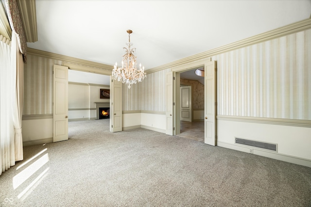 carpeted spare room featuring crown molding and a notable chandelier