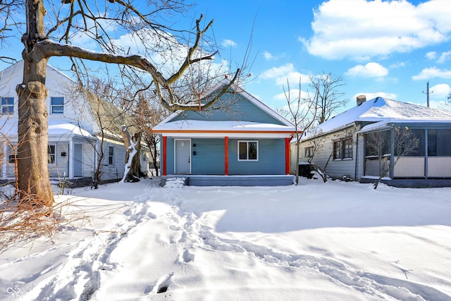 snow covered back of property with a porch