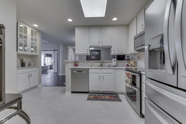 kitchen with white cabinets, a barn door, stainless steel appliances, and sink