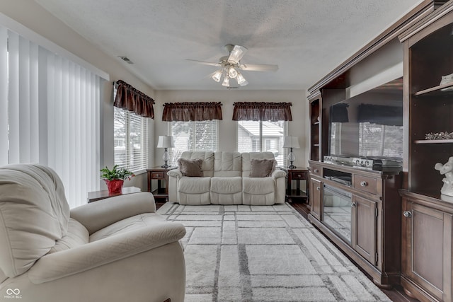 living room with light wood-type flooring, a textured ceiling, and ceiling fan