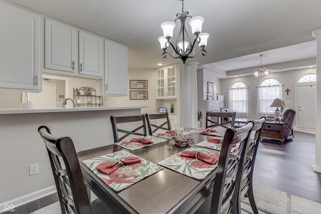 dining area with dark hardwood / wood-style flooring, ceiling fan with notable chandelier, and ornate columns